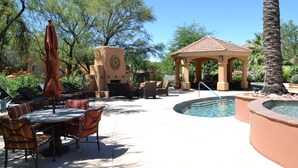 A pool area with lounge chairs, a gazebo, and a clock tower.