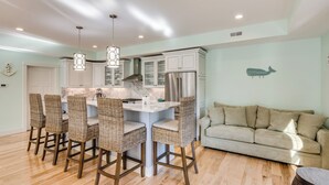 Una cocina moderna con armarios blancos, una isla central con taburetes de bar y un refrigerador de acero inoxidable.
