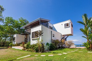 Una moderna casa a due piani con tetto piatto, ampie finestre e un piccolo garage adiacente.