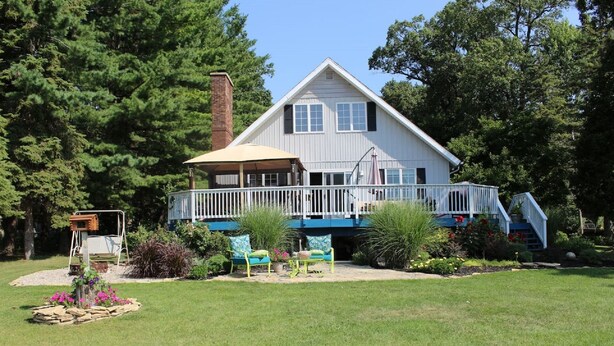 A two-story house with a covered porch, a brick chimney, and a small deck. - Turtle Cove Lakefront APT.  10 min from MIS, 40 min to Ann Arbor (Clarklake)