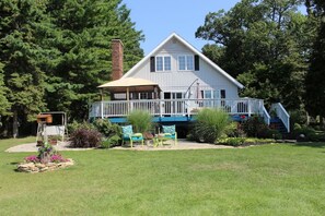 A two-story house with a covered porch, a brick chimney, and a small deck. - Turtle Cove Lakefront APT.  10 min from MIS, 40 min to Ann Arbor (Clarklake)