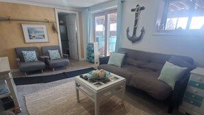 A living room with a sofa, armchairs, a coffee table, and a rug. There is a door leading to a balcony with a view. - Turtle Cove Lakefront APT.  10 min from MIS, 40 min to Ann Arbor (Clarklake)