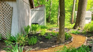 A garden pathway with mulch and plants, surrounded by trees and a wooden structure. - Turtle Cove Lakefront APT.  10 min from MIS, 40 min to Ann Arbor (Clarklake)
