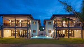 A two-story building with a swimming pool in the center, surrounded by a well-maintained lawn.