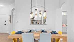 Een eethoek met een houten tafel, gele stoelen en een hanglamp.