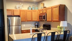 A kitchen with wooden cabinets, stainless steel appliances, a granite countertop, and a bar area with chairs. - **Bluegrass Getaway** (Lexington)