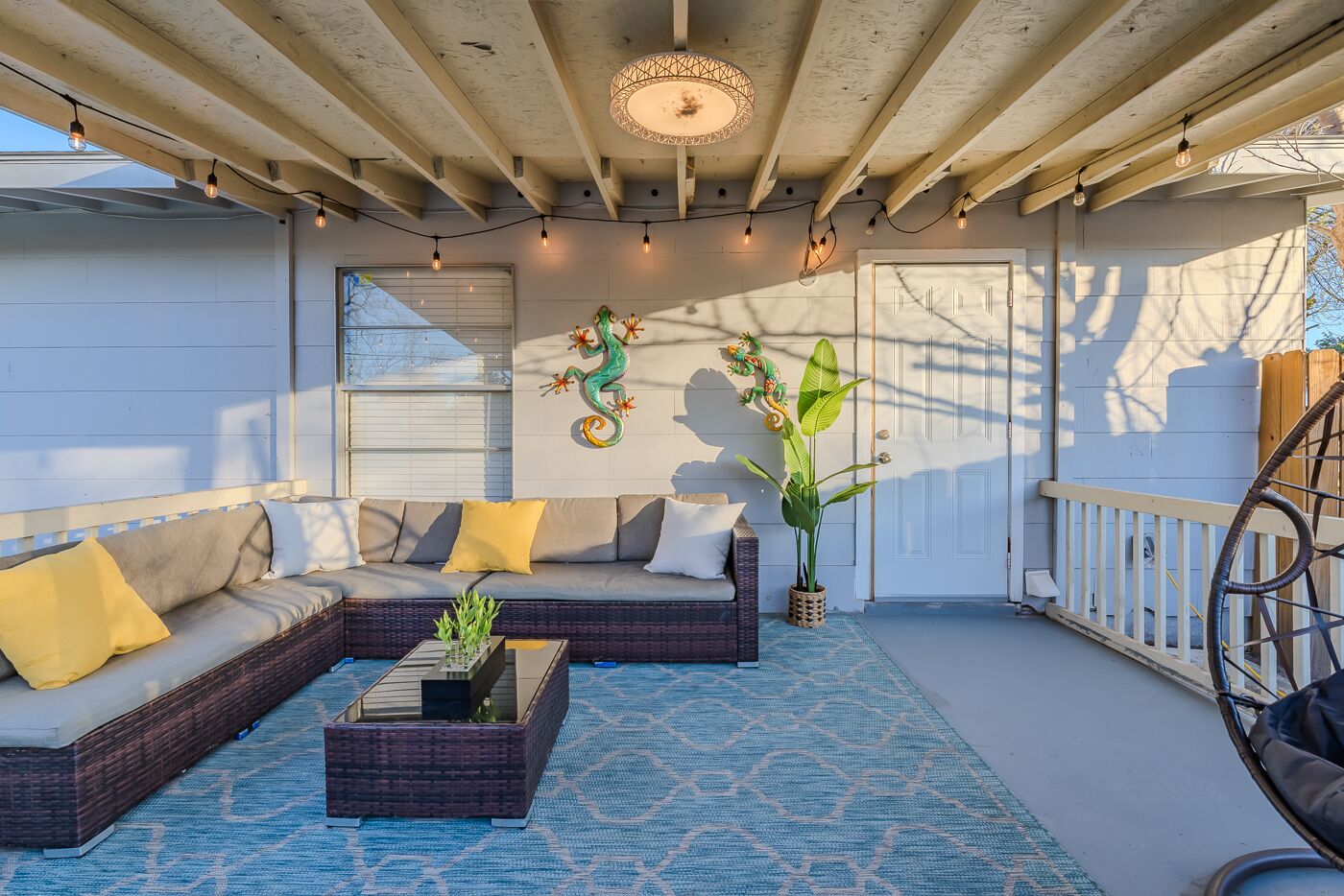 An outdoor patio with a sofa set, a coffee table, and decorative plants.