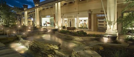 Un hotel con una cascada de piedra, mobiliario exterior y una tienda Tiffany's.
