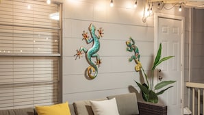 Una sala de estar acogedora con un sofá, adornos en la pared y una planta grande.