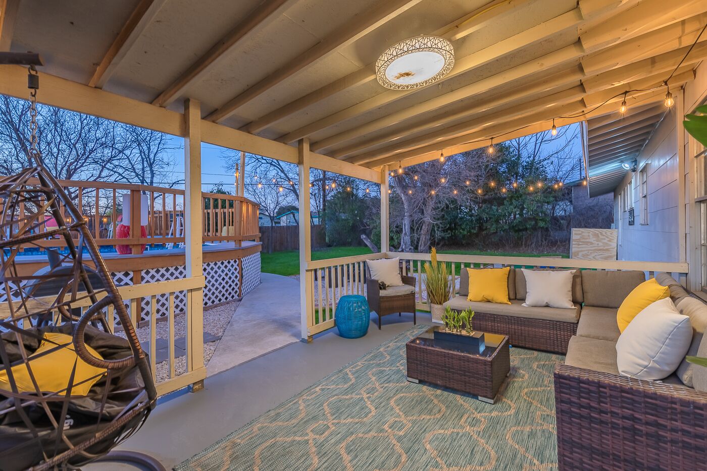 An outdoor covered patio with seating, a play structure, and string lights.