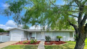 A single-story house with a front garage, a well-maintained lawn, and a tree in the front yard. - Private Pool, Gameroom, Fire pit & BBQ near the Medical center (San Antonio)