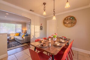 A dining area with a wooden table set for four, surrounded by red chairs, and a cozy living area with a sofa and a lamp. - Private Pool, Gameroom, Fire pit & BBQ near the Medical center (San Antonio)
