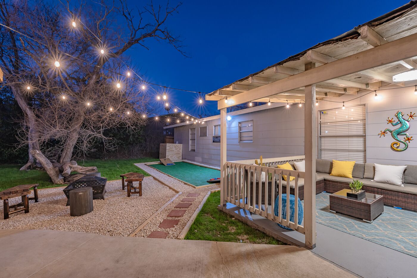 Un patio techado al aire libre con piscina, zona de estar y luces colgantes.