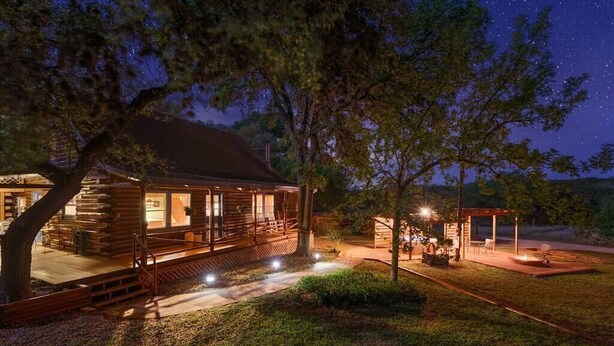 Une cabane en rondins avec un porche, un foyer et un espace extérieur aménagé avec des sièges.