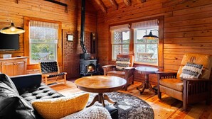 Un intérieur chaleureux de chalet en bois, avec une cheminée, des meubles en cuir et de grandes fenêtres.