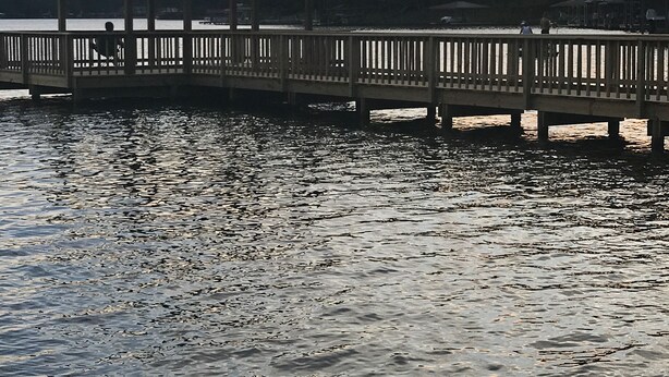 Een houten pier met een tuinhuis aan het einde, dat zich uitstrekt over kalm water.