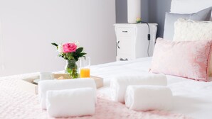 A neatly made bed with white linens, a pink floral pillow, and a glass of orange juice on a tray. - Historic center of Ponta Delgada - Balcony and Free Wifi (Ponta Delgada)