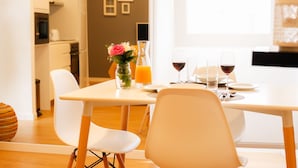 A dining area with a table set for two, a vase with flowers, and a bottle of orange juice. - Historic center of Ponta Delgada - Balcony and Free Wifi (Ponta Delgada)