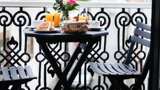 A balcony with a table set for breakfast, including croissants, orange juice, and a vase with flowers. - Historic center of Ponta Delgada - Balcony and Free Wifi (Ponta Delgada)