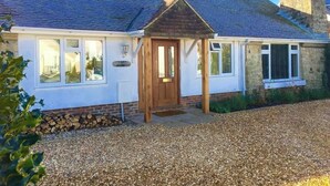 A house with a gravel driveway, a wooden front door, and a chimney.