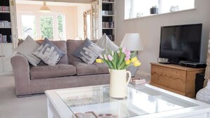 A living room with a sofa, a glass coffee table, a television, and a bookshelf.