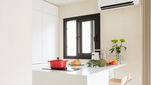 A modern kitchen with white cabinetry, a black-framed window, a red pot, a loaf of bread, a pineapple, and a fruit bowl. - the best location at the center of the city (Sevilla)