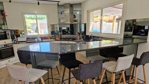Une cuisine moderne dotée d’un îlot central, de tabourets de bar et offrant une vue sur l’extérieur.