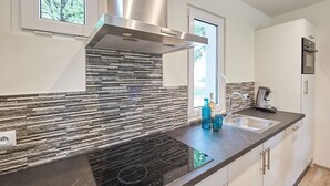Eine moderne Küche mit Steinrückwand, Edelstahl-Dunstabzugshaube und einem eingebauten Herd.