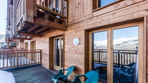 Un edificio de madera con balcón, ventanas amplias y asientos al aire libre.