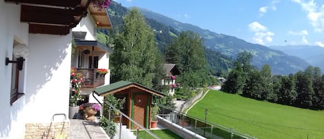 Un balcon donnant sur une vallée verdoyante et des montagnes.