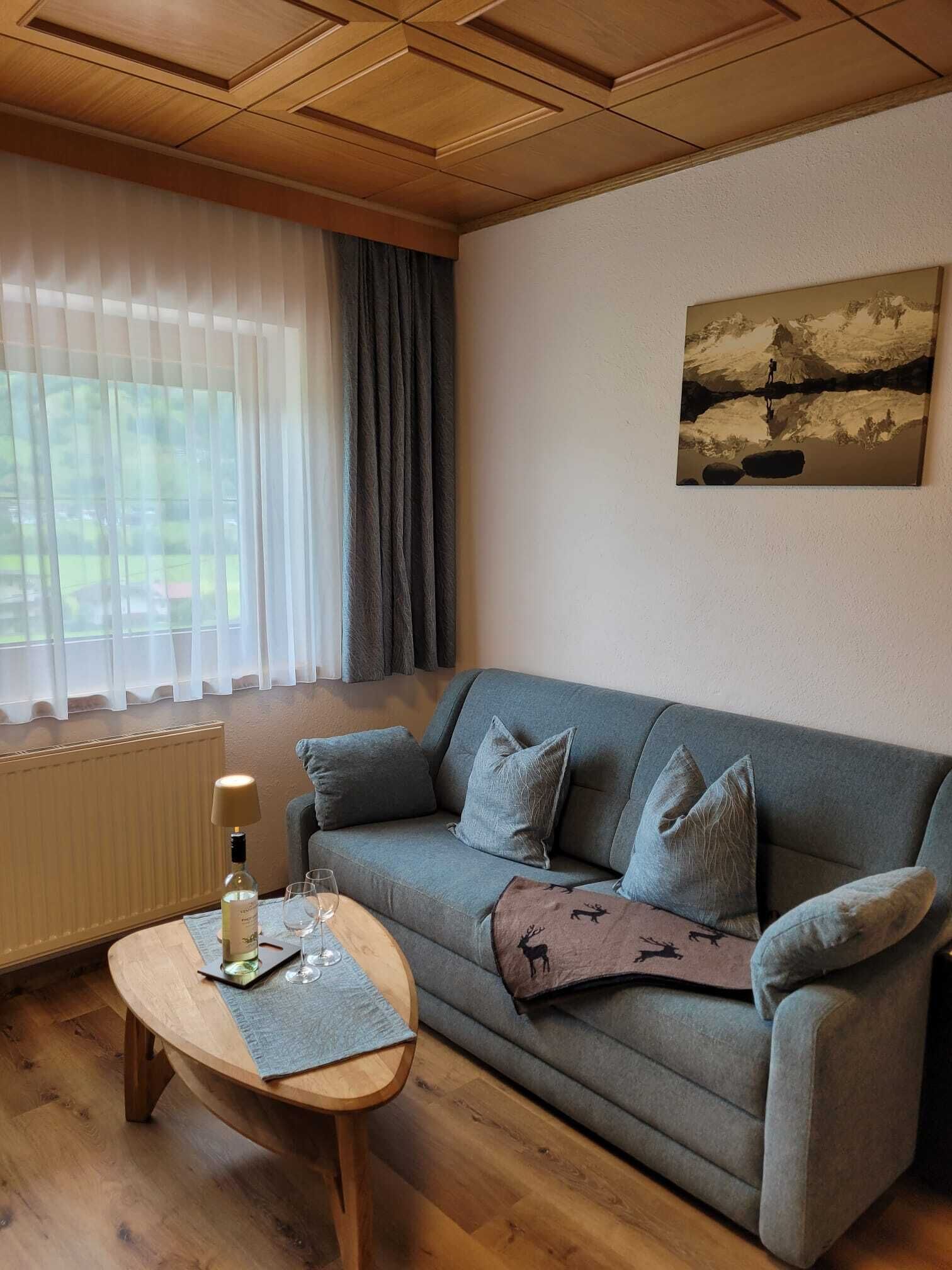 A cozy living room with a grey sofa, a wooden coffee table, and a painting on the wall.