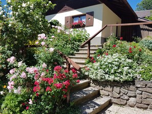 Staircase leads to a traditional chalet with a lush garden.