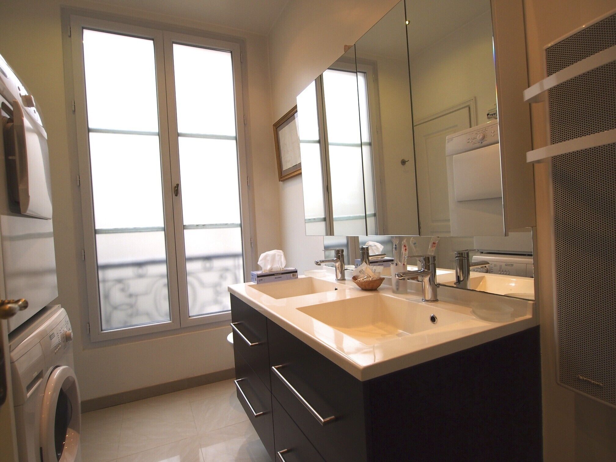 Een moderne badkamer met twee wastafels, een grote spiegel en een raam.
