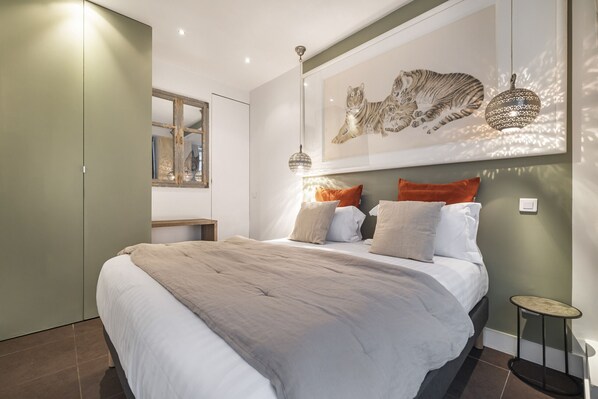 A modern bedroom with a large bed, a headboard with a tiger print, and a small bedside table.