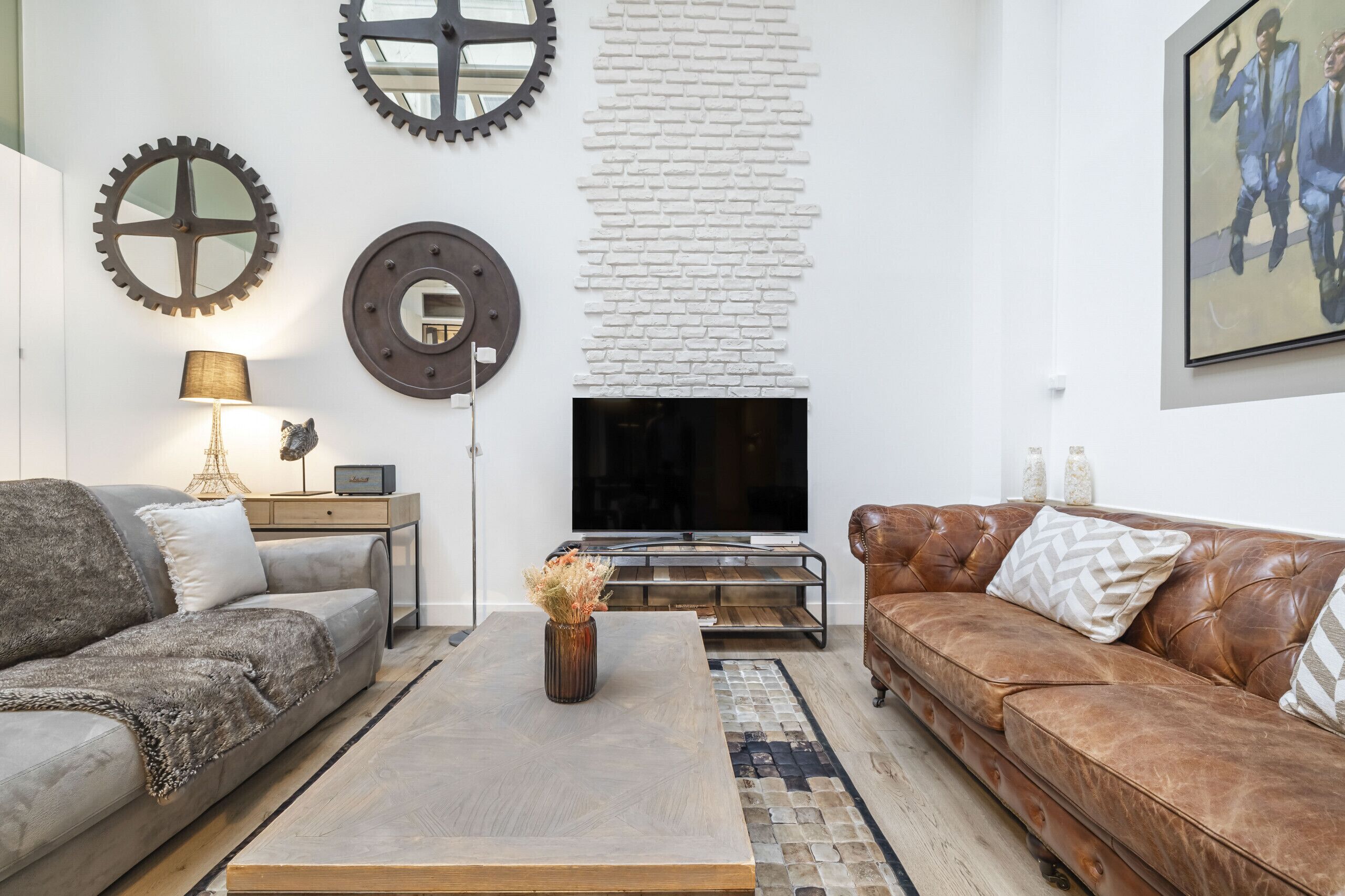 Ein Wohnzimmer mit Sofa, Couchtisch und Fernseher. Dekorative Wandelemente und ein Teppich sind ebenfalls vorhanden.