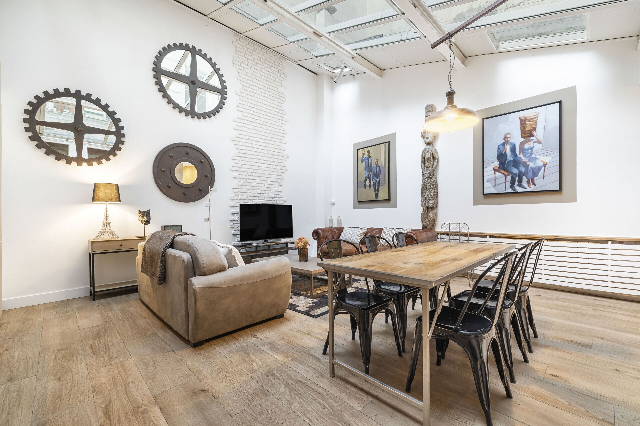 A modern living room with a sofa, TV, and dining area with chairs and a table.
