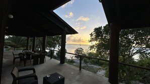 An outdoor seating area with a view of the sea and a sunset. - Beautiful Beachfront Island Home, Private Dock, Village Transportation Included (Placencia)