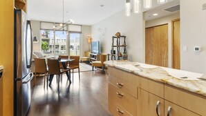 A modern kitchen with a marble countertop, wooden cabinets, and pendant lighting. - Pearl Pad: Enjoy River, Shopping, Dining.  Balcony, Garage  and free EV chging! (Portland)