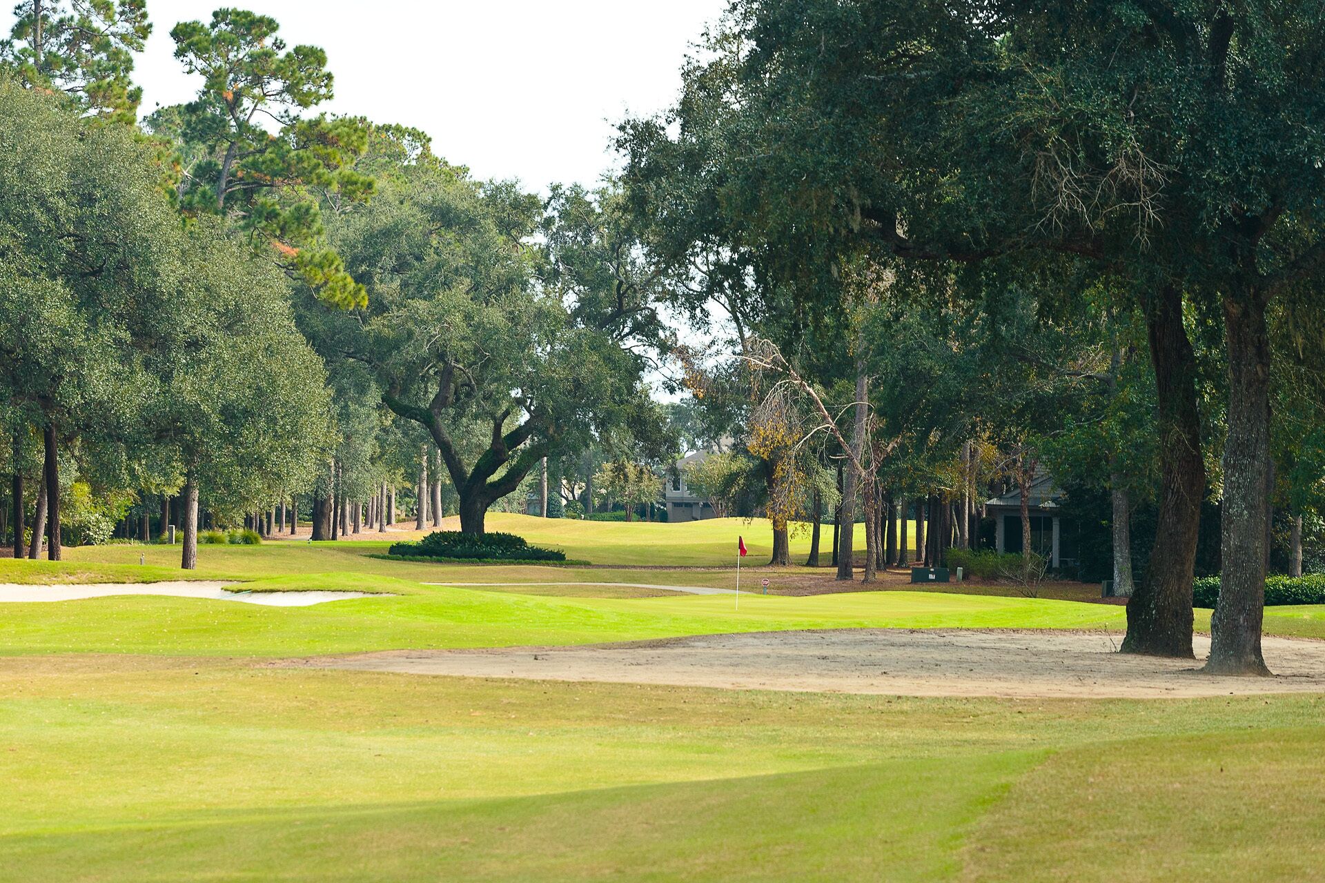 A golf course with a well-maintained fairway, sand bunkers, and a clubhouse in the background.