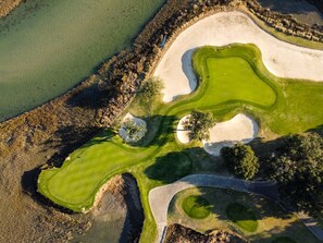 An aerial view of a golf course with sand bunkers, water hazards, and a well-maintained green. - 130-3 Stillwood Drive, Pawleys Plantation (Pawleys Island)
