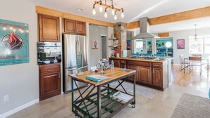 Una cocina amplia con armarios de madera, una isla central y una lámpara colgante.
