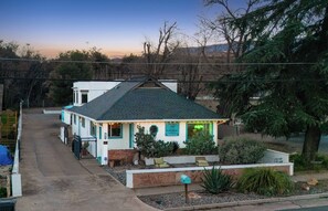 Un bâtiment à deux étages, doté d’un toit végétalisé, d’une enseigne indiquant qu’il s’agit d’une maison d’hôtes et d’une enseigne lumineuse au néon.