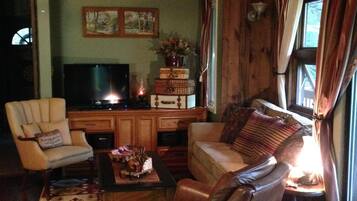 A cozy living room with a television, a wooden cabinet, a sofa, and a chair.