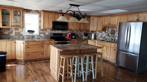 Una cocina con armarios de madera, un refrigerador de acero inoxidable, encimera de granito y una isla central con taburetes.