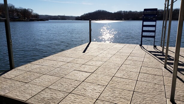 Un muelle con vistas a un lago tranquilo y colinas lejanas.