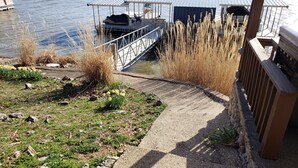 Un muelle con zona de estar techada, una parrilla y vista al agua.