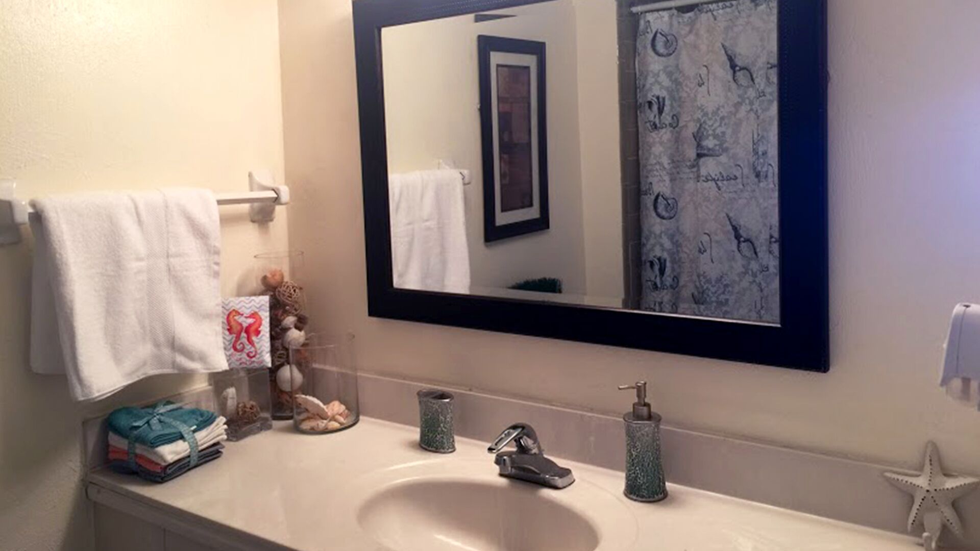 Un baño con un lavabo blanco, un espejo y un perchero para toallas.