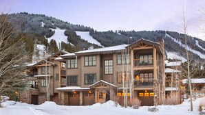 A multi-story lodge with a stone facade, multiple balconies, and a ski slope in the background. - Perfect location makes for easy access to downtown, Snow King and more (Jackson)