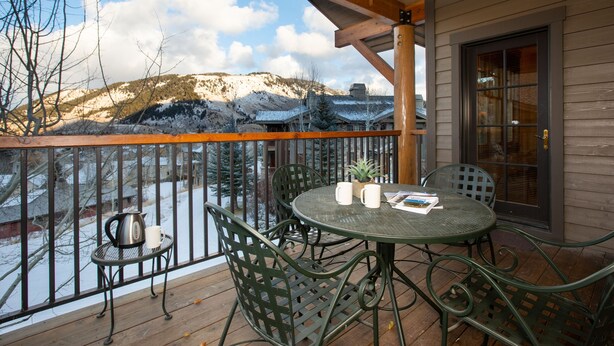 A wooden deck with a metal table and chairs, overlooking a snowy mountain. - Perfect location makes for easy access to downtown, Snow King and more (Jackson)