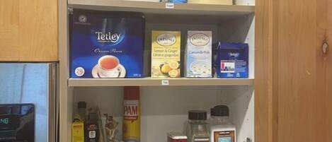 A kitchen with a coffee maker, a kettle, and various food items on shelves.
